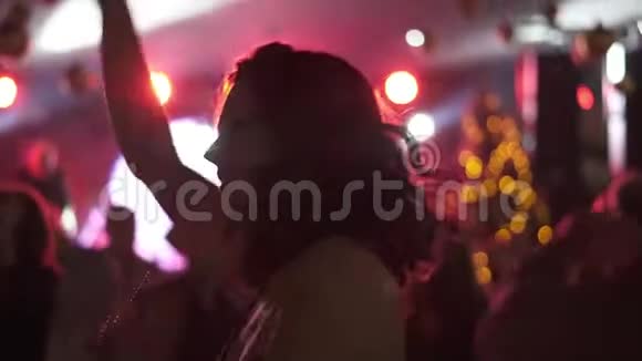 一个年轻女孩在一群人的背景下在迪斯科舞厅跳舞的肖像视频的预览图