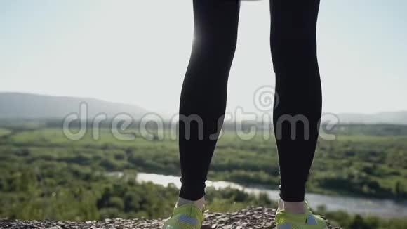 快关门年轻的运动女子站在悬崖边夕阳下明亮的夏日绿色森林体育运动视频的预览图