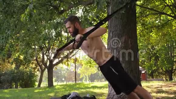 有胡子的年轻肌肉男在树旁做健身运动4K慢莫特写镜头视频的预览图