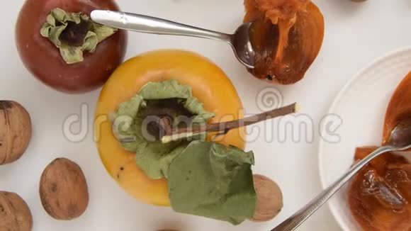 相机沿着秋天的水果移动白色背景的生柿子和坚果视频的预览图