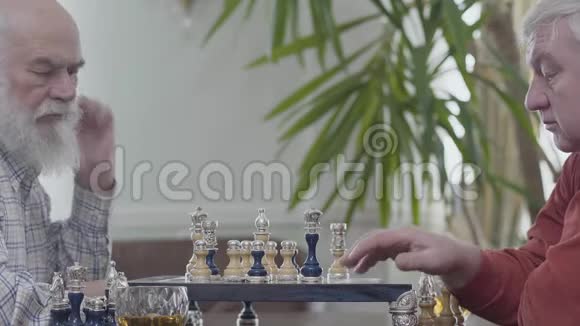 两个老朋友坐在家里下棋高加索老人邻居在室内愉快地下棋智力视频的预览图