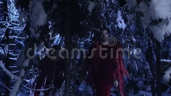 年轻的男人和女人在寂静的夜晚慢慢地走在白雪皑皑的冬林里视频的预览图