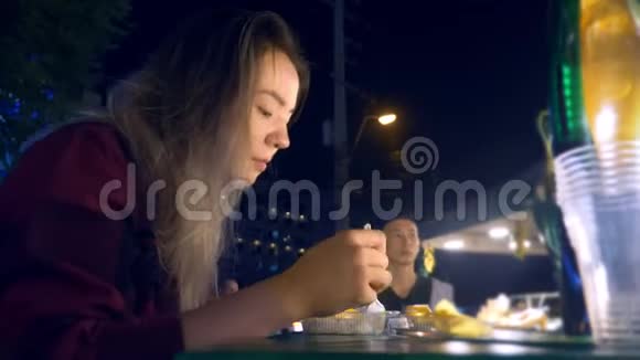 年轻的亚洲女孩晚上在户外吃街头食品视频的预览图
