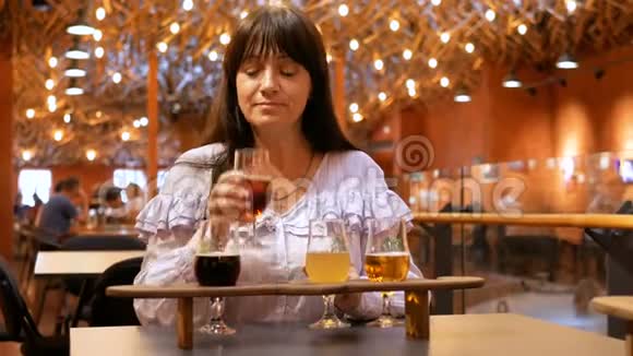 成年妇女在木架上用小玻璃杯品尝几种啤酒烤面包机不太喜欢这种饮料视频的预览图