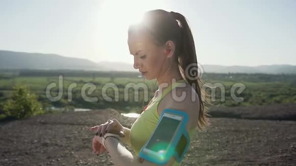 健身运动员女孩跑得很快速度快身穿手机袖标山上有智能手机触摸屏视频的预览图
