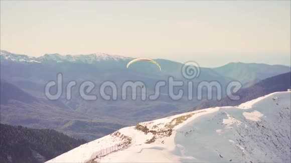 运动员乘坐红色滑翔伞飞越雪山山峰雪山背景下的滑翔伞视频的预览图