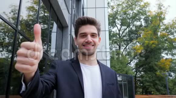 赢家成功办公区域穿商务服装的布鲁内特年轻人微笑着对着镜头竖起大拇指快乐视频的预览图