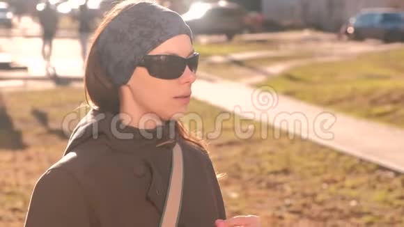 年轻的黑发女人戴着太阳镜在街上喝着瓶子里的水打开瓶子喝水视频的预览图