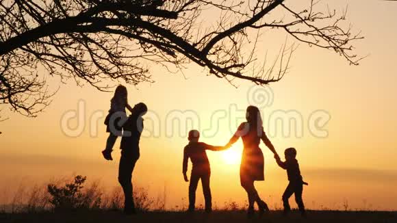 日落时分一家人在草地上共度时光的剪影视频的预览图
