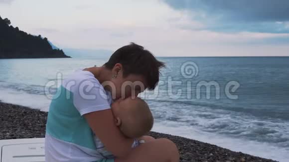 妈妈手里的熟睡的孩子沙滩上视频的预览图