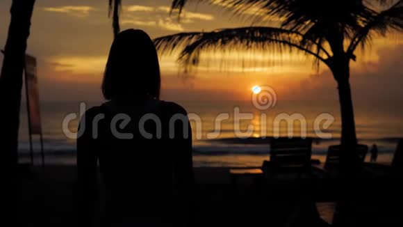 年轻健康的女人在日落海浪的海滩上练习瑜伽夕阳下坚定自信的女人视频的预览图