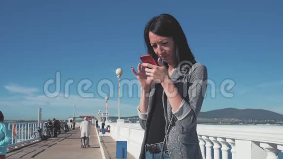美丽的女人在海滩上使用手机年轻女性在户外智能手机上发短信的画像视频的预览图