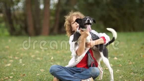 一个穿着白色衬衫和牛仔裤的男孩拥抱他的狗带着宠物在公园散步照顾和维护狗视频的预览图