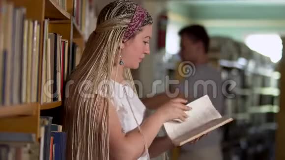 美丽的女孩正在图书馆翻阅一本书视频的预览图