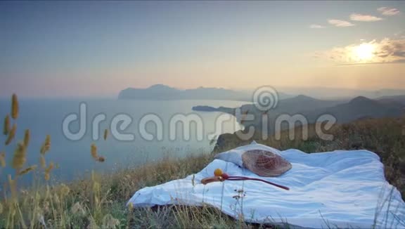日落时分草地上铺着一张毯子上面有帽子和水果上面有美丽的照片上面有山顶视频的预览图
