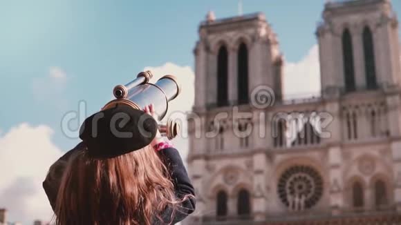 贝雷帽里的女孩通过硬币望远镜看慢动作巴黎圣母院女孩子用望远镜观察视频的预览图