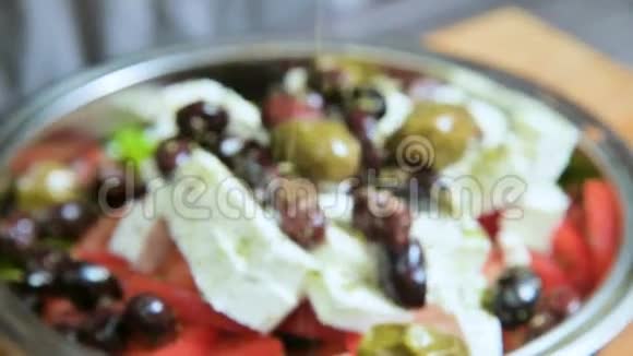 在希腊蔬菜沙拉中手动添加调味料的特写素食健康食品视频的预览图