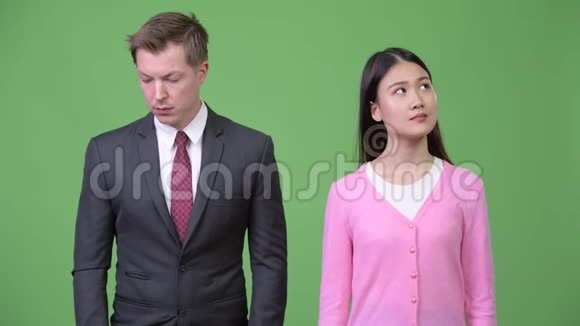 年轻快乐的亚洲女人和年轻悲伤的商人在一起思考视频的预览图