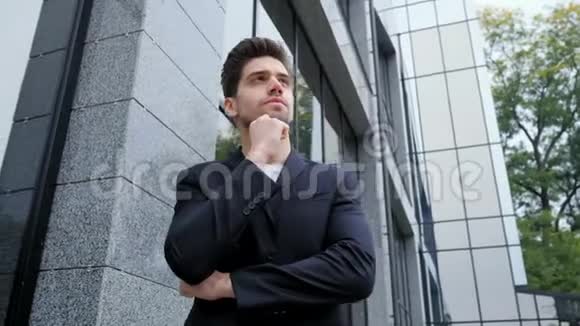 城市中年轻成功的沉思商人的肖像在办公楼背景上穿商务夹克的人帅哥视频的预览图