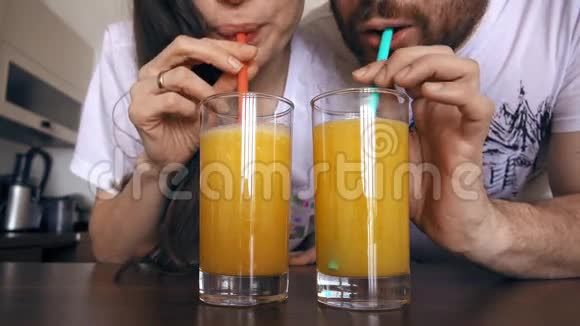 年轻的女人和男人用吸管喝橙汁健康的生活方式或有趣的竞争概念4K型视频的预览图