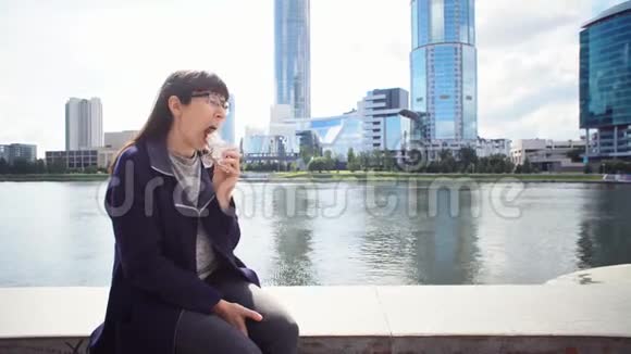 快乐的女商人在市中心河岸附近吃多纳串视频的预览图