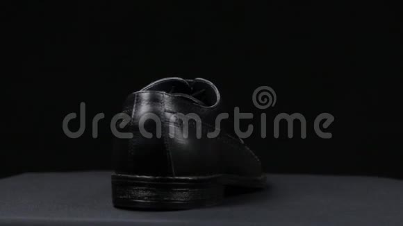 旋转一个时尚的经典黑色鞋带在黑色背景视频的预览图