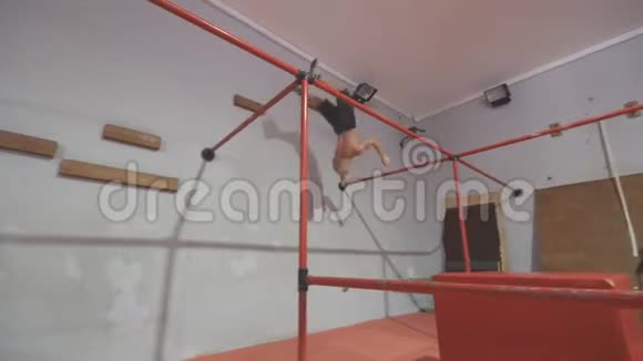 在健身房训练时年轻人跳在金属结构上在室内表演杂技的白人概念视频的预览图