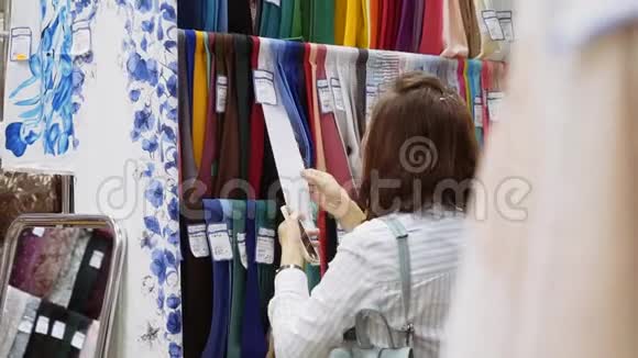 纺织和纺织商店里的女人选择一种布料来缝制一件连衣裙视频的预览图