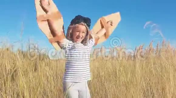 女孩扮演一个经典的飞行员戴着毛皮帽子眼镜和翅膀由纸板作为玩具儿童视频的预览图