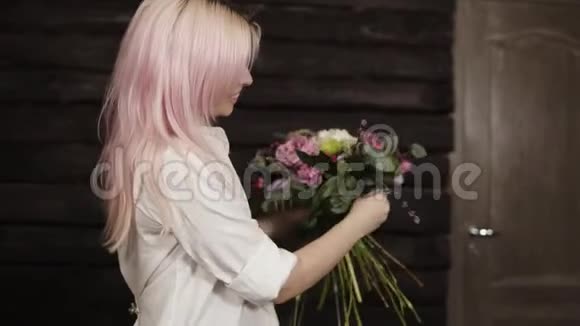 一位粉红色的头发的年轻女子做花束的设计用柳枝补充构图微笑视频的预览图