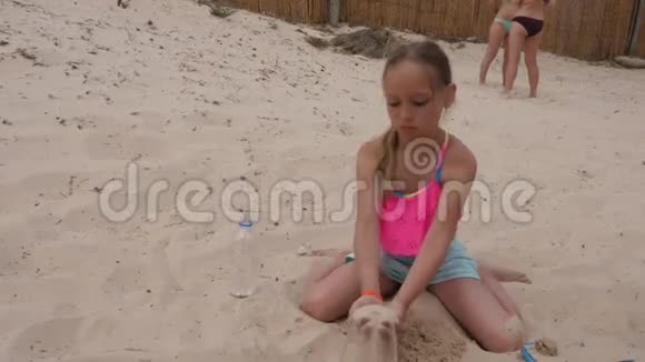 可爱的女孩子玩沙子坐在海滩上视频的预览图