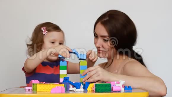 妈妈和她的小女儿坐在桌边玩一个忙于建筑工程的女孩妈妈视频的预览图