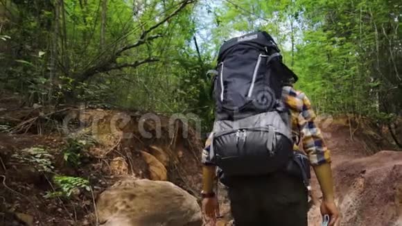 徒步旅行者带着背包在自然森林中行走和寻找的慢动作视频的预览图