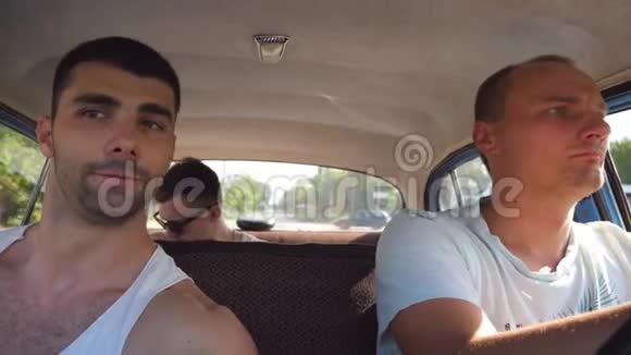 三个朋友在乡村公路上开老式汽车坐在复古车前座的年轻人视频的预览图