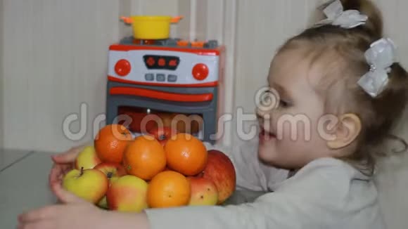 一个可爱的小女孩展示了她对水果的热爱孩子坐在一张桌子旁吃橘子橘子和苹果视频的预览图