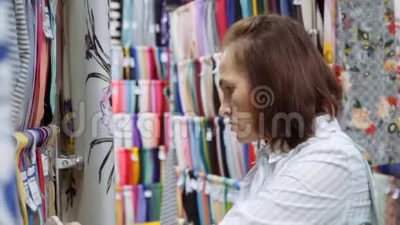 纺织和纺织商店里的女人选择一种布料来缝制一件连衣裙视频的预览图