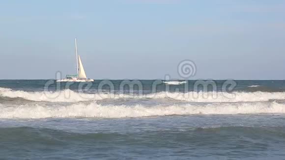 一艘白帆的游艇矗立在海里游客骑在海岸外在阳光明媚的日子里在海中散步视频的预览图