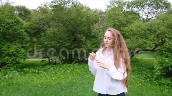 欧洲女孩长着非常长的卷发让泡泡和运行在大自然女模特在公园里玩得很开心慢视频的预览图