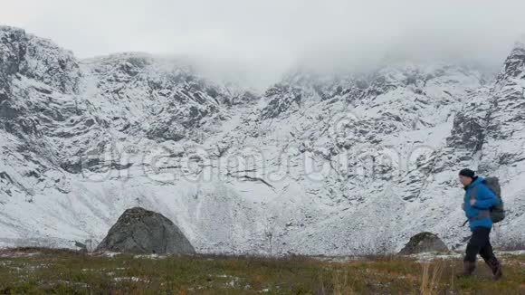 一个背着背包的人独自一人在山里旅行它沿着高高的雪峰视频的预览图