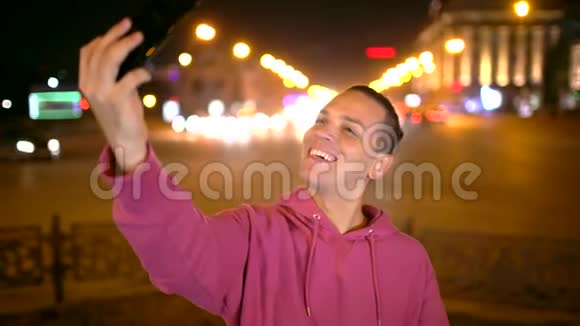 年轻人带着美丽的微笑在夜城自拍技术概念视频的预览图