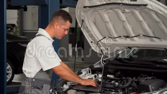 专业汽车修理工在修理汽车时使用笔记本电脑视频的预览图