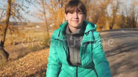 秋天公园里在黄树的背景下小女孩骑自行车上路视频的预览图