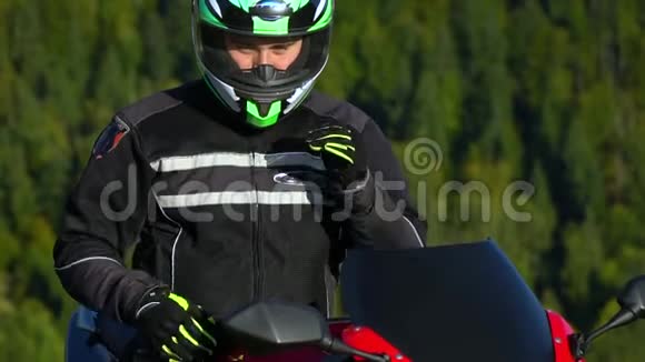骑摩托车的人一个骑摩托车在山里的年轻帅哥特写那家伙摘下头盔视频的预览图