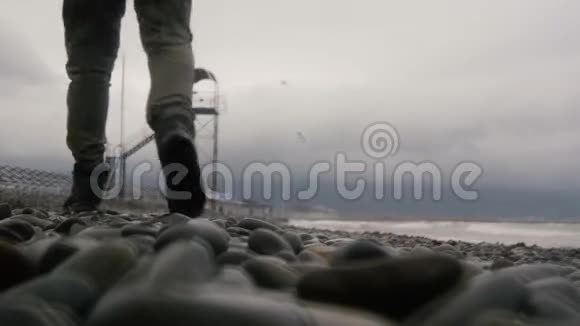一个穿长靴的人朝着塔走去空荡荡的秋日海滩视频的预览图
