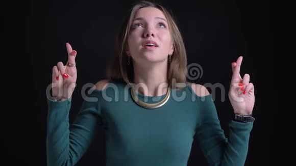 年轻的黑发白种人女孩的肖像手势交叉手指标志以显示希望的黑色背景视频的预览图