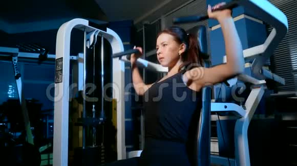 坐在模拟机上锻炼身体那个女孩正在健身房里健身视频的预览图