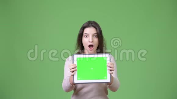 年轻的美女展示数码平板电脑看上去很震惊视频的预览图