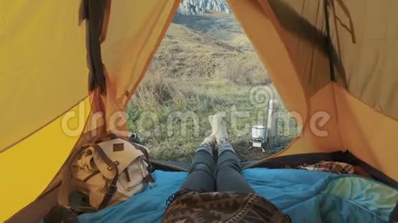 露营的女人躺在帐篷里穿着登山靴在度假时放松从帐篷的角度视频的预览图