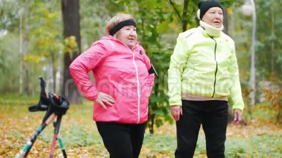 成熟的女人在秋天的公园里做体操双脚视频的预览图