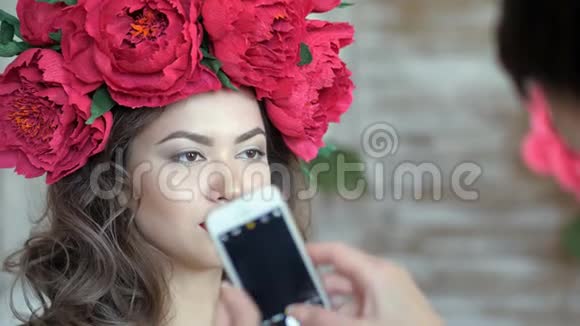 化妆师和模特一起工作女人正在智能手机上给一个女孩模特拍照视频的预览图